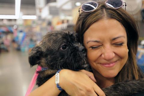 woman hugging a small brown dog